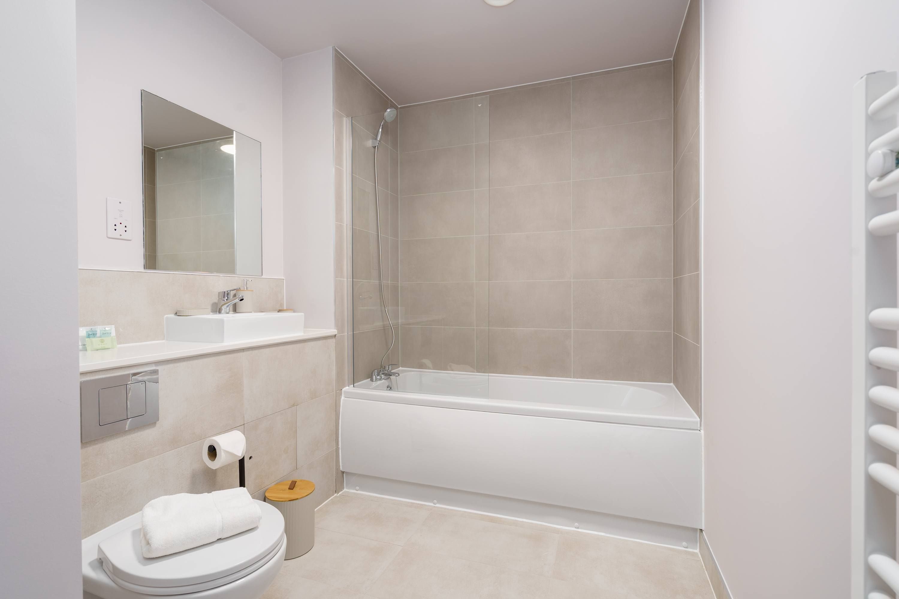 A modern bathroom with a bathtub, toilet, sink, and mirror.