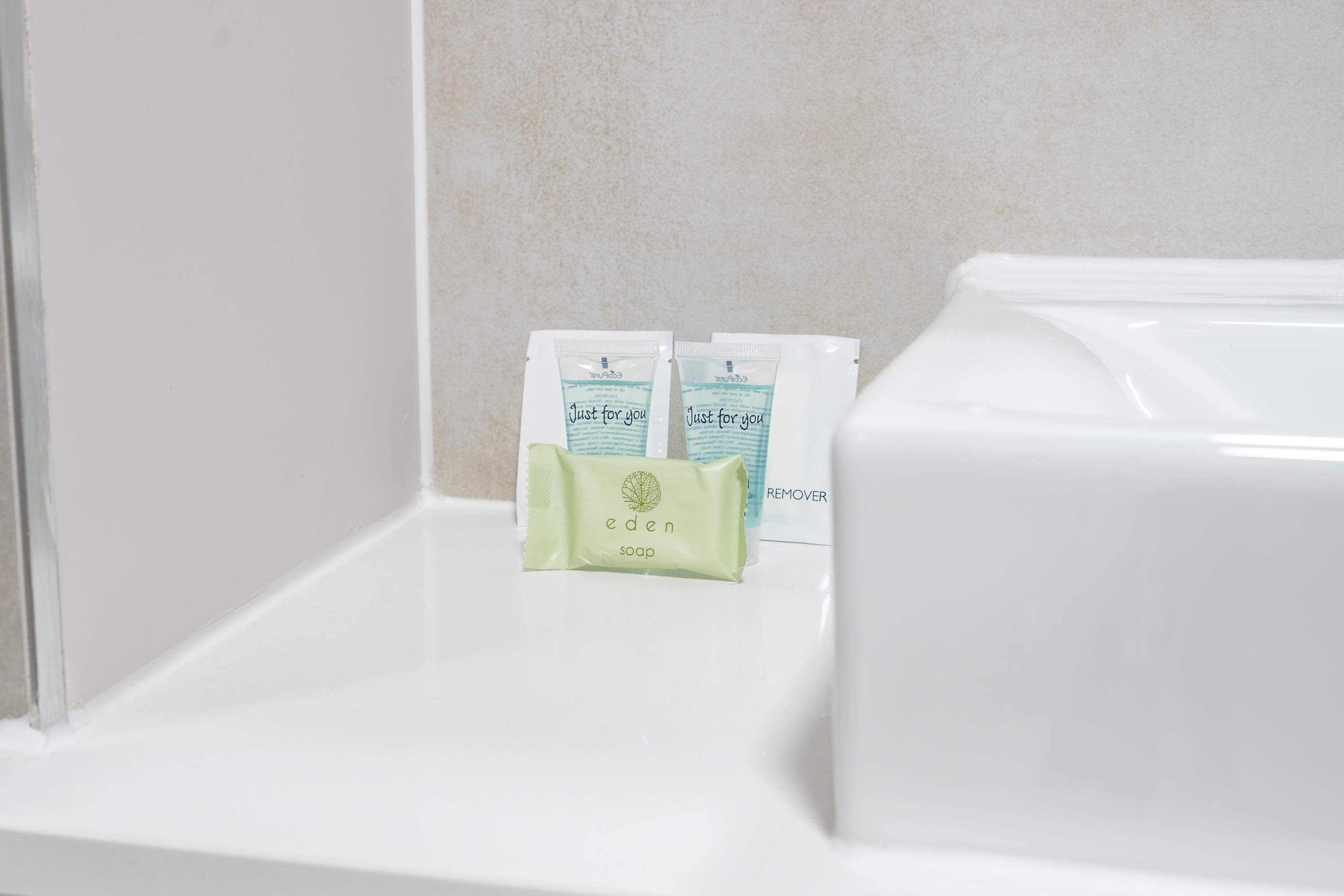 A bathroom with a white sink, two soap dispensers labeled 'eden soap,' and a 'REMOVER' sign.