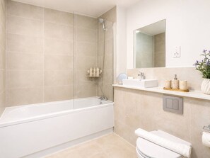 Et moderne badeværelse med badekar, bruser, håndvask og toilet.