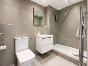 A modern bathroom with a toilet, sink, and glass-enclosed shower. - Sleeps 6 - 2BR Stay - Free Parking - Manchester (Manchester)