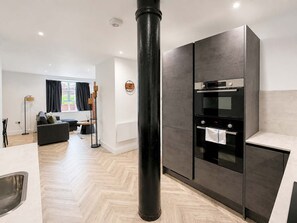 A modern kitchen with a built-in oven and a dining area with a sofa and a floor lamp. - Sleeps 6 - 2BR Stay - Free Parking - Manchester (Manchester)