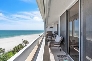 Ein Balkon mit Blick auf den Strand, ein Deckenventilator und ein Sessel.