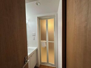 Ein schmaler Flur mit einer Tür zu einem Raum mit einer matten Glasverkleidung.