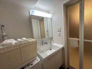 Ein Badezimmer mit Waschbecken, Spiegel, Handtuchhalter und Duschbereich.