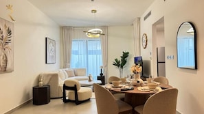 Ein modernes Wohnzimmer mit einer Couch, einem Esstisch, Stühlen und einem Fernseher.