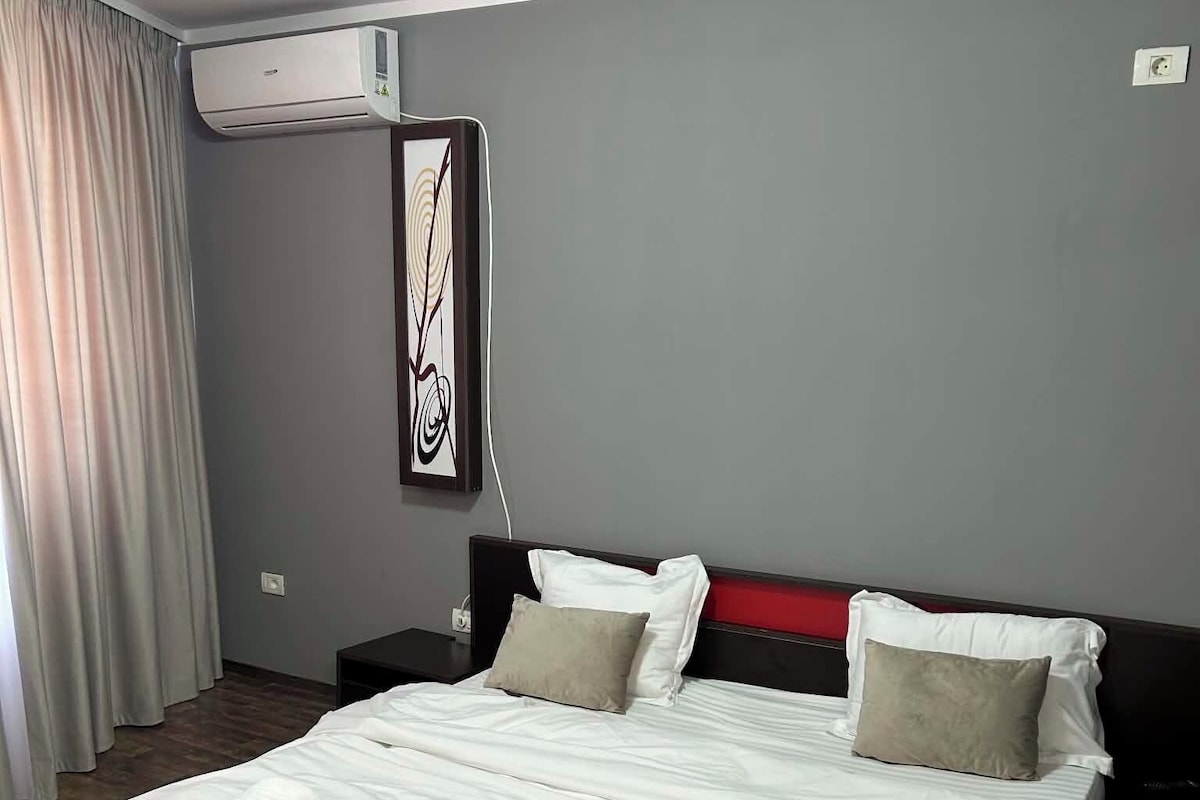 Een hotelkamer met een groot bed, een nachtkastje, een airconditioning en een kunstwerk aan de muur.