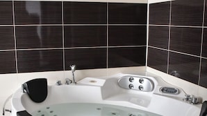 A modern bathroom with a freestanding bathtub, a handheld showerhead, and a built-in seat. - Hotel Artimino (Timișoara)