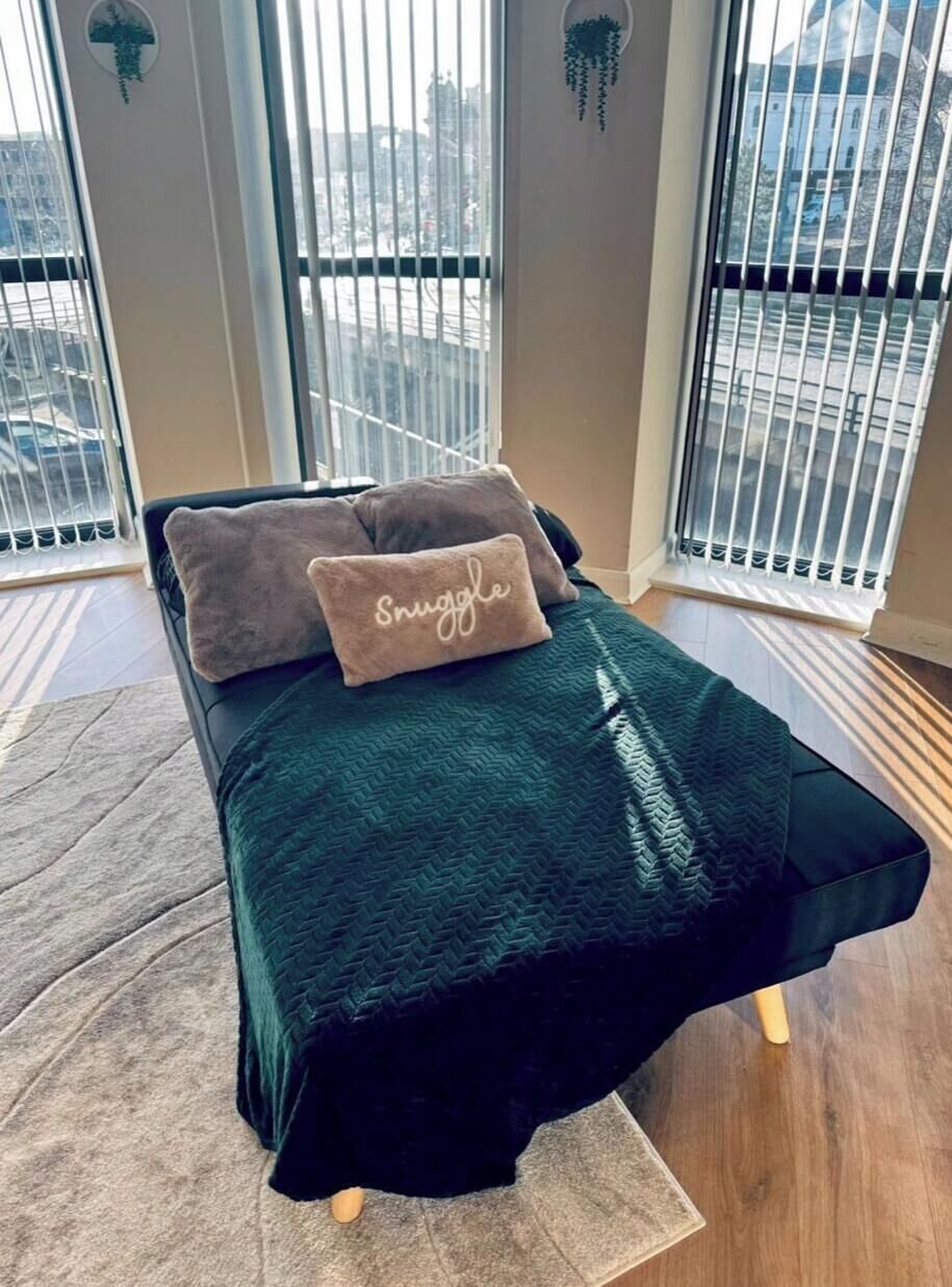 Una cama con una colcha verde oscuro y dos almohadas, una con la palabra 'Snuggle'.