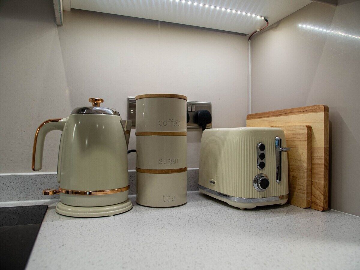 Une petite cuisine équipée d’une machine à café, d’un récipient pour le sucre et le thé, et d’un grille-pain.