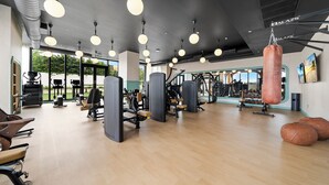 A gym with exercise equipment, large windows, and a punching bag. - Private Residence at Nomad Wynwood Residencs - 532 (Miami)