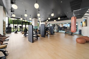 Ein Fitnessstudio mit Trainingsgeräten, großen Fenstern und einem Sandsack.