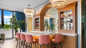 A bar area with a marble countertop, multiple bar stools, and a mirrored wall with shelves displaying glasses and bottles. - Private Residence at Nomad Wynwood Residencs - 532 (Miami)