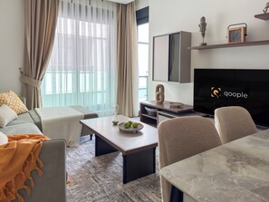 Una sala moderna con sofá, mesa de centro, televisor y comedor.