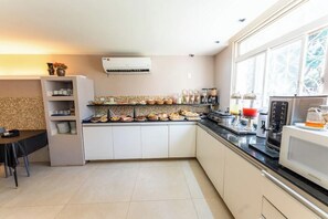 A modern kitchen with a dining area, a built-in oven, a microwave, and a window with a decorative view. - Riviera Hotel Brasilia (Brasília)