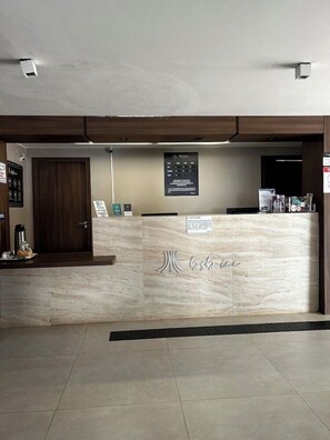 A reception desk with a marble counter, a wooden door, and a wall-mounted sign. - Riviera Hotel Brasilia (Brasília)