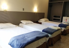 A hotel room with three single beds, a wardrobe, and a small desk with a chair. - Riviera Hotel Brasilia (Brasília)