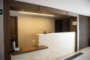 Una recepción con un mostrador de madera, una máquina de café y un cartel en la pared.