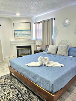 Een slaapkamer met een bed, een open haard, een schilderij en een kamerbreed tapijt.