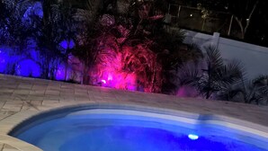 Una piscina a forma curva, circondata da una pavimentazione e palme.