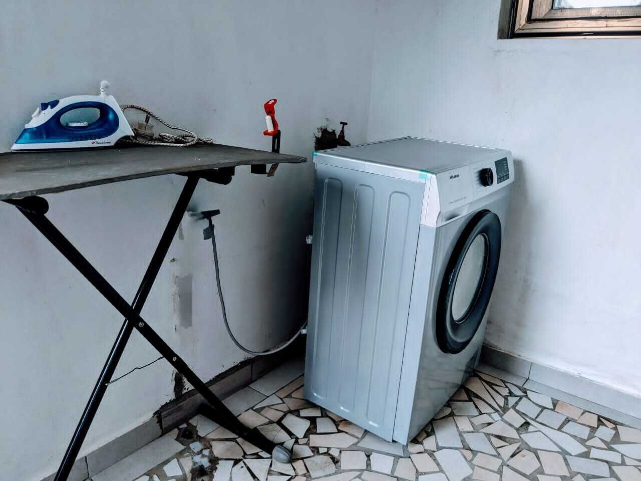 Un espacio pequeño para la lavandería con lavadora y tabla de planchar.