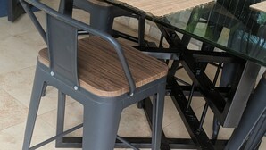 A glass-top table with a woven placemat, a metal chair with a cushioned seat, and a potted plant. - Villa Kabiessi L’élégance et le confort réunis (Abomey Calavi)