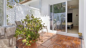 Eine Terrasse mit Holzboden, einem Topfpflanzen und einem weißen Gitterzaun.