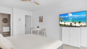 Ein Schlafzimmer mit Bett, Schreibtisch, Sessel, Fernseher und Deckenventilator.