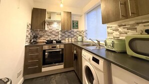 Una cucina compatta con forno, microonde ed elettrodomestici inclusi.