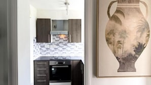 Una cucina con mobili in legno scuro, forno integrato e rivestimento a piastrelle.