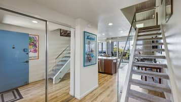 A hotel interior with a staircase, a kitchen area, and a view of the outdoors.