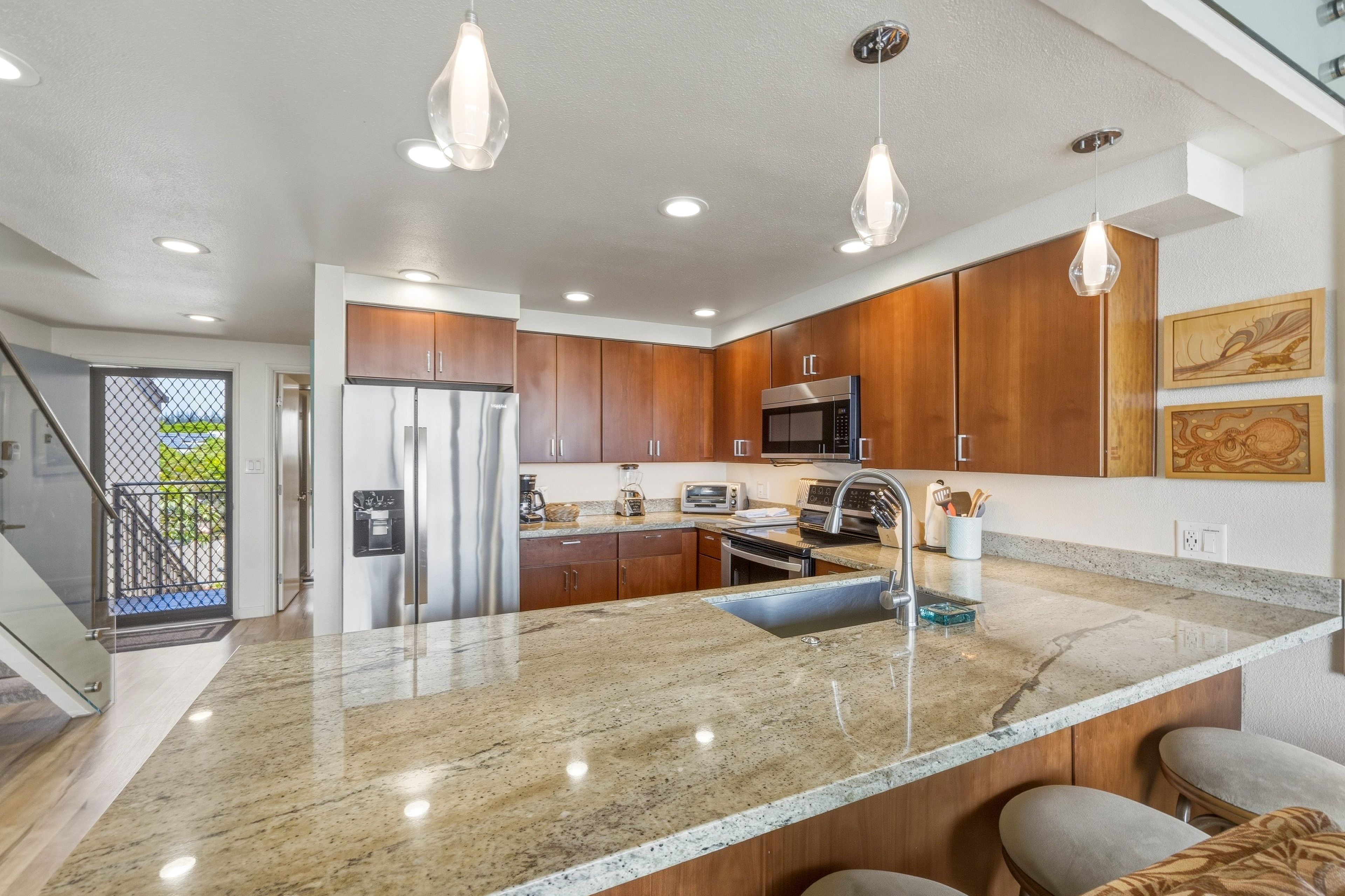 A modern kitchen with granite countertops, stainless steel appliances, and wooden cabinets.