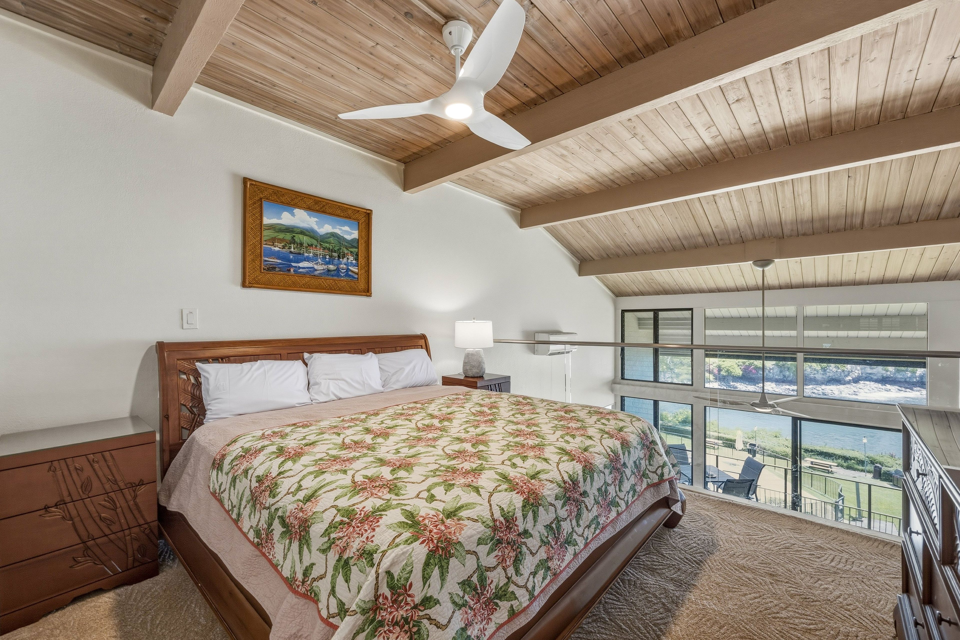 Una camera da letto con un letto, un comodino, un quadro e un balcone con vista.