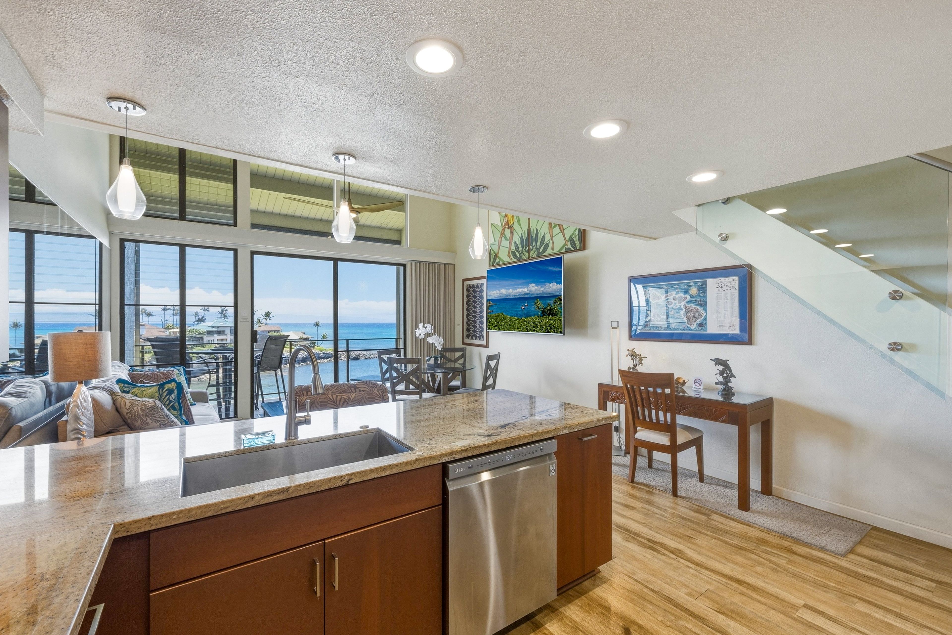 A modern kitchen with a large island, stainless steel appliances, and a view of the ocean.