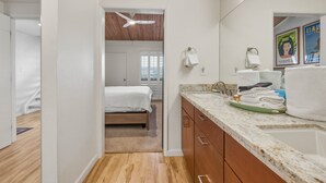 A hotel room with a bed, a bathroom with a sink, and a shower. - Ocean View 2BR Loft Near Napili Beach - Unit C34 (Lahaina)