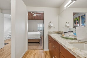 Una habitación de hotel con cama, baño con lavamanos y ducha.