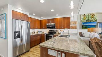 A modern kitchen with wooden cabinets, stainless steel appliances, a granite countertop, and a central island.