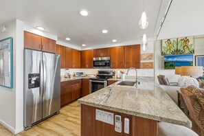 A modern kitchen with wooden cabinets, stainless steel appliances, a granite countertop, and a central island.