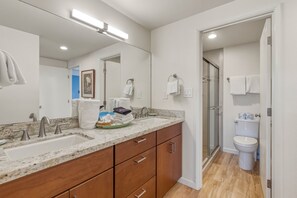Un baño moderno con tocador doble, cabina de ducha de vidrio y retrete.
