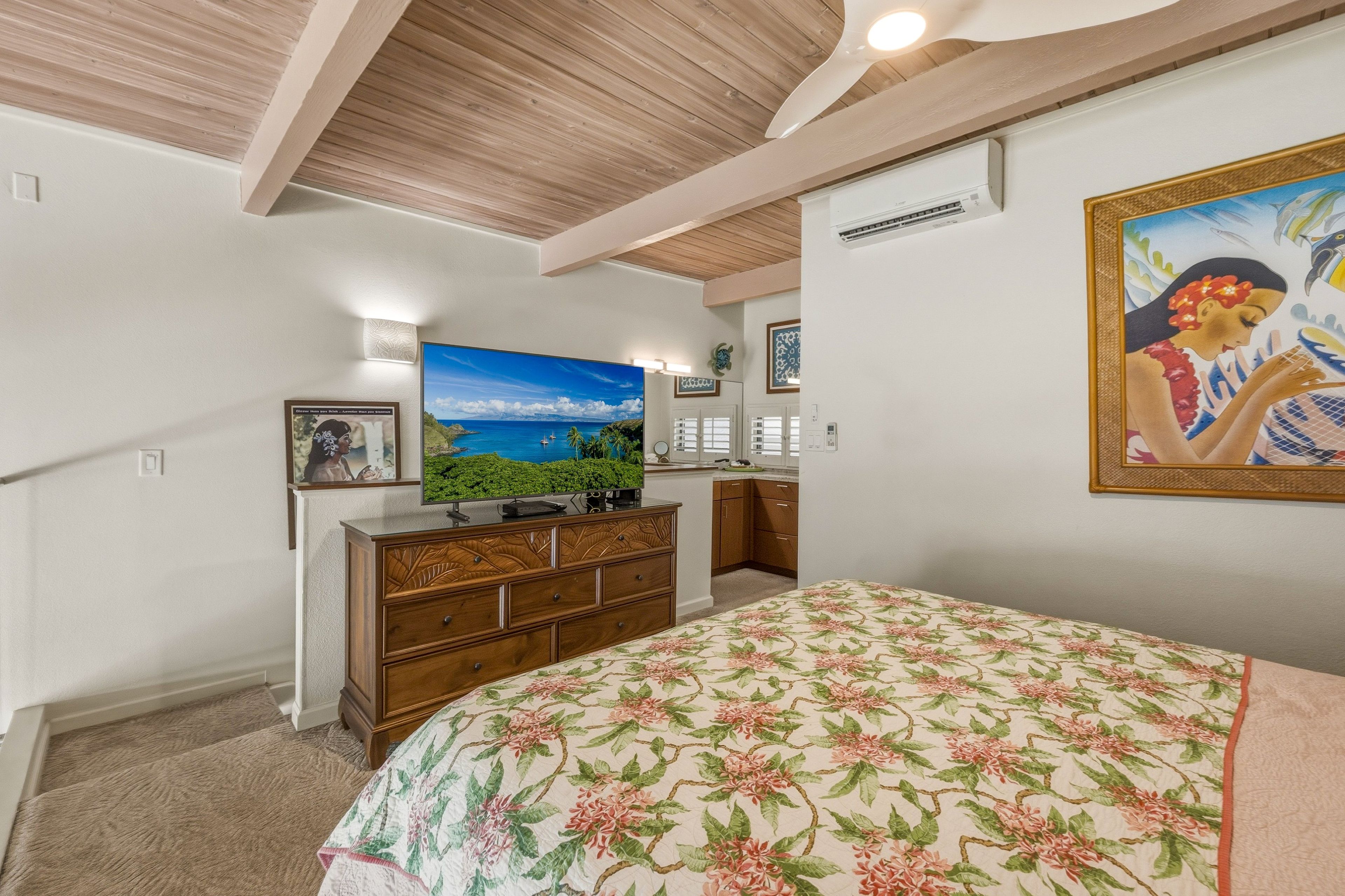 A bedroom with a bed, a dresser, a television, and a painting on the wall.