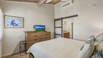 A bedroom with a bed, a dresser, a television, and a painting on the wall.