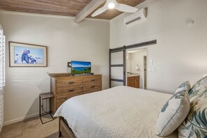 A bedroom with a bed, a dresser, a television, and a painting on the wall.