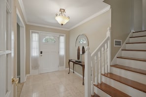 A hallway with a white door, a wooden console table, a mirror, and a staircase with white railings. - Private Pool Oasis 15 Mins To World Cup Sleeps 10 4 Bedroom Home (Decatur)