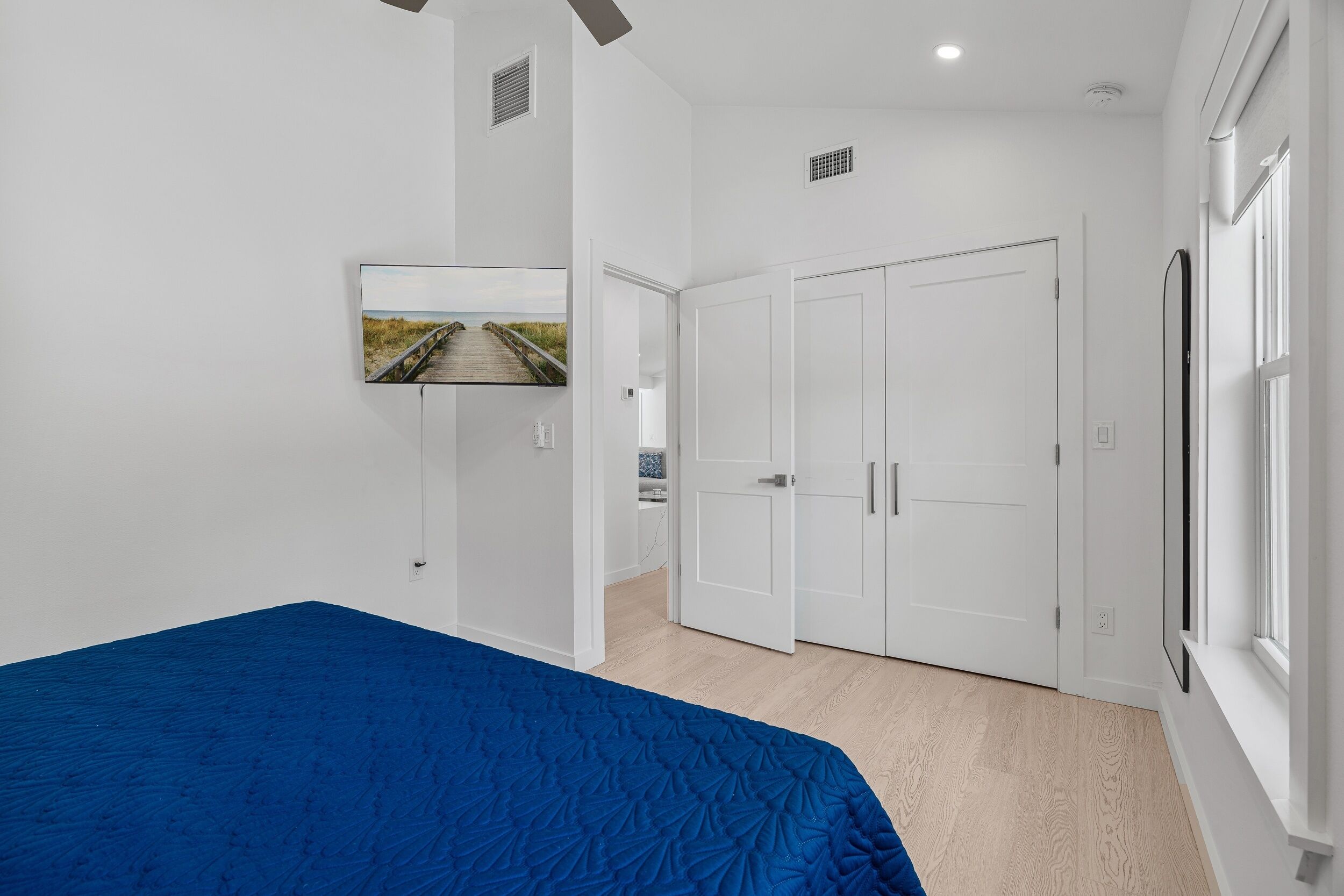 Een slaapkamer met een bed, een kledingkast, een deur en een raam.