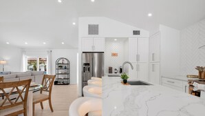 A modern kitchen with white cabinetry, a marble island, and a built-in refrigerator. - Ringside On Ringling 4 Bedroom Home (Sarasota)