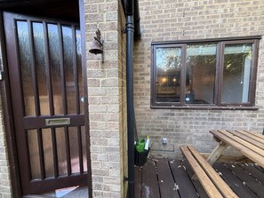 A wooden door with a window above it, a bench, and a wall-mounted bell. - The Secluded Corner Wimbledon Chase With Parking (London)