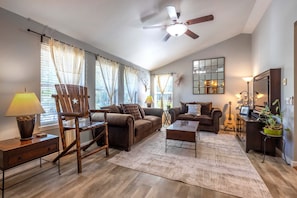 A living room with a ceiling fan, two sofas, a coffee table, a lamp, a guitar, and a potted plant. - Easy Stay 3 Bedroom Home (Hood River)