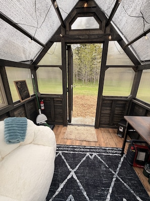 A cozy room with a large window, a white couch, a black rug, and a wooden table.