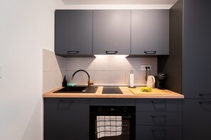 Eine moderne Küche mit grauen Schränken, einem schwarzen Geschirrspüler und einer Holzarbeitsplatte.