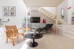 Ein modernes Wohnzimmer mit einem runden Tisch, zwei Stühlen, einem Fernseher und einer Treppe.