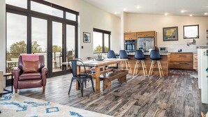 Un amplio espacio de estar con un ventanal grande, una mesa de comedor y una cocina equipada con electrodomésticos modernos.